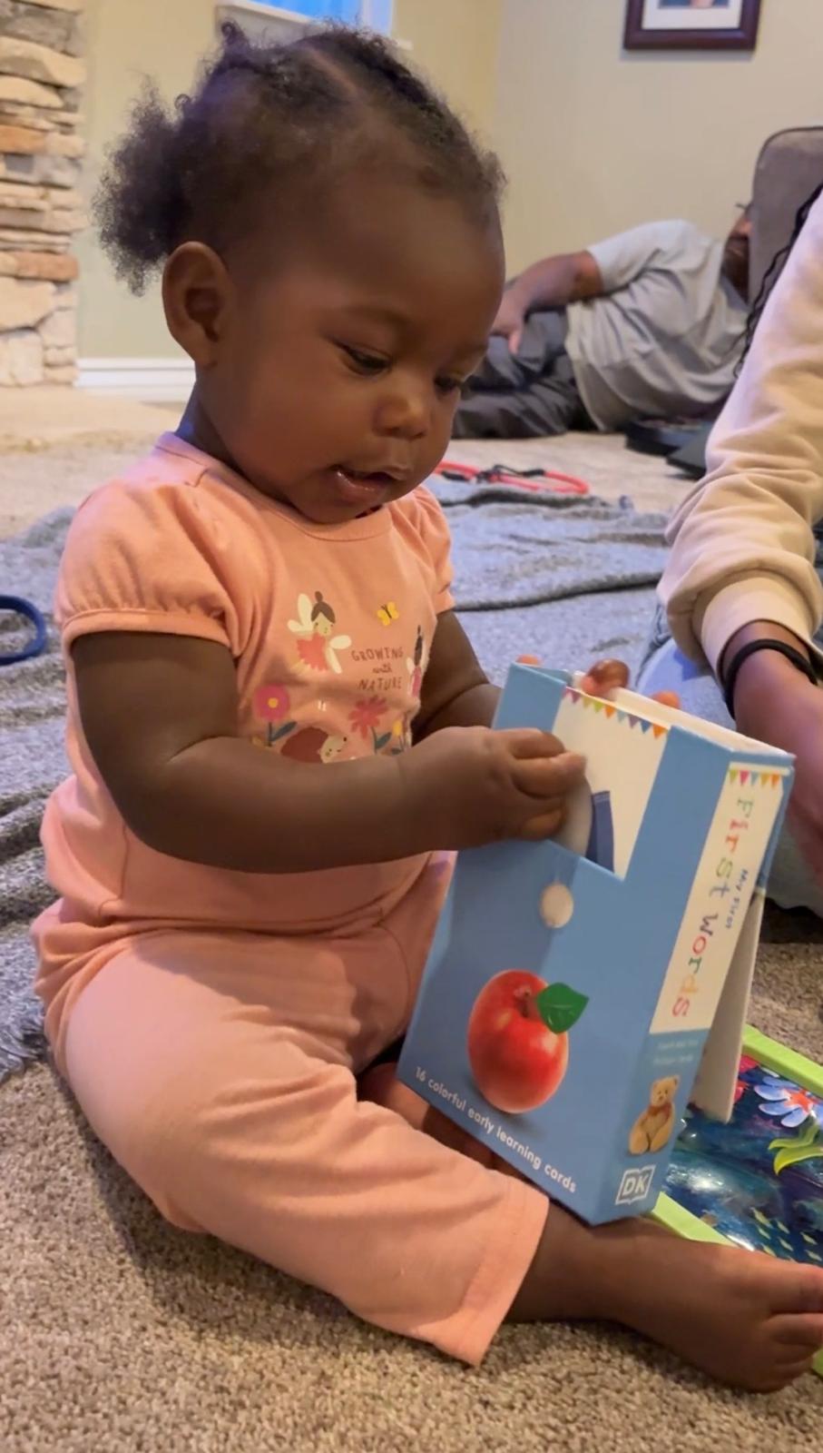 A baby girl holding a set of colorful early learning flashcards. From homegrownthinking.com